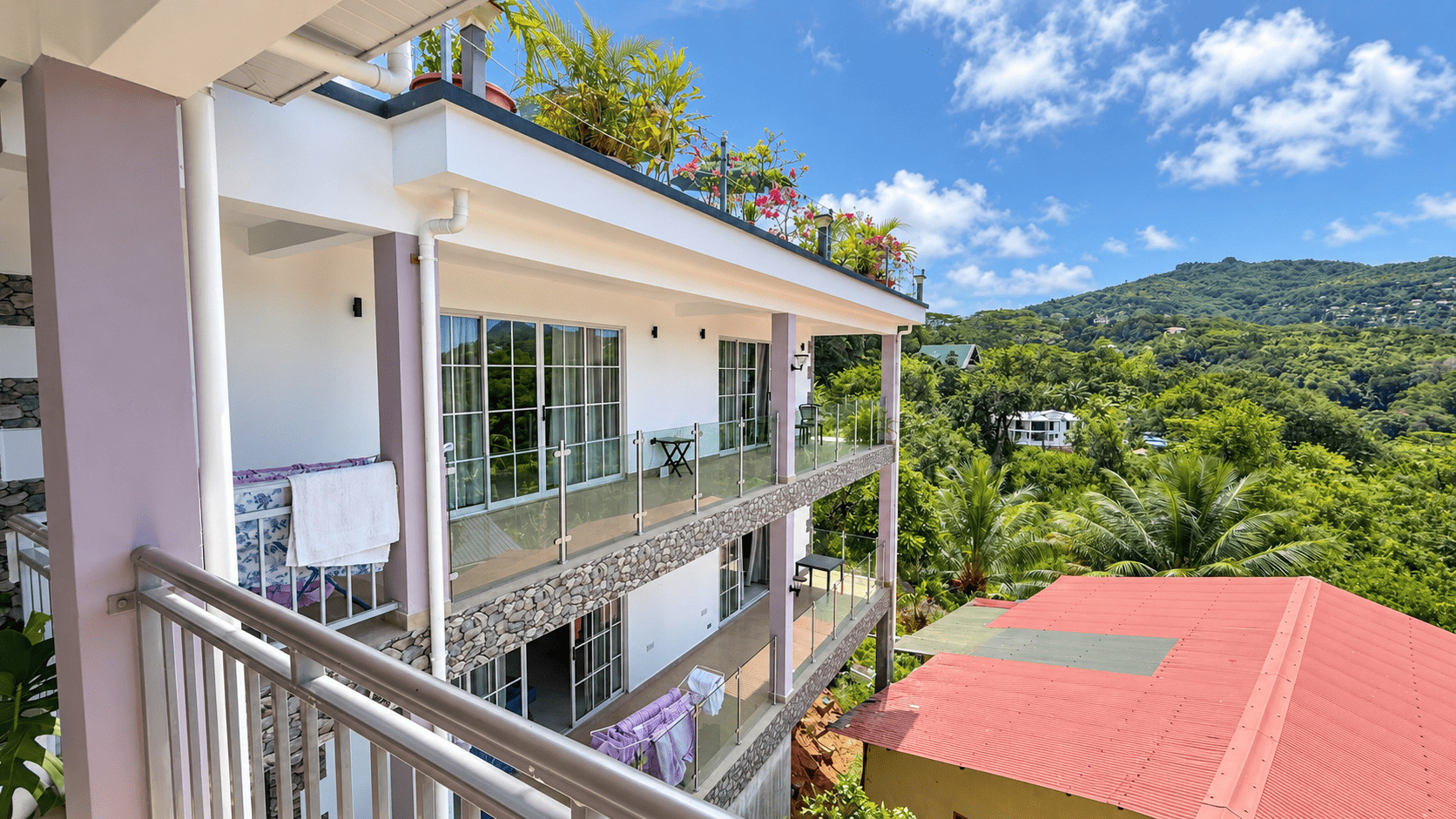 Balcony of a Creole Cottage apartment overlooking the green slope and village roofs
