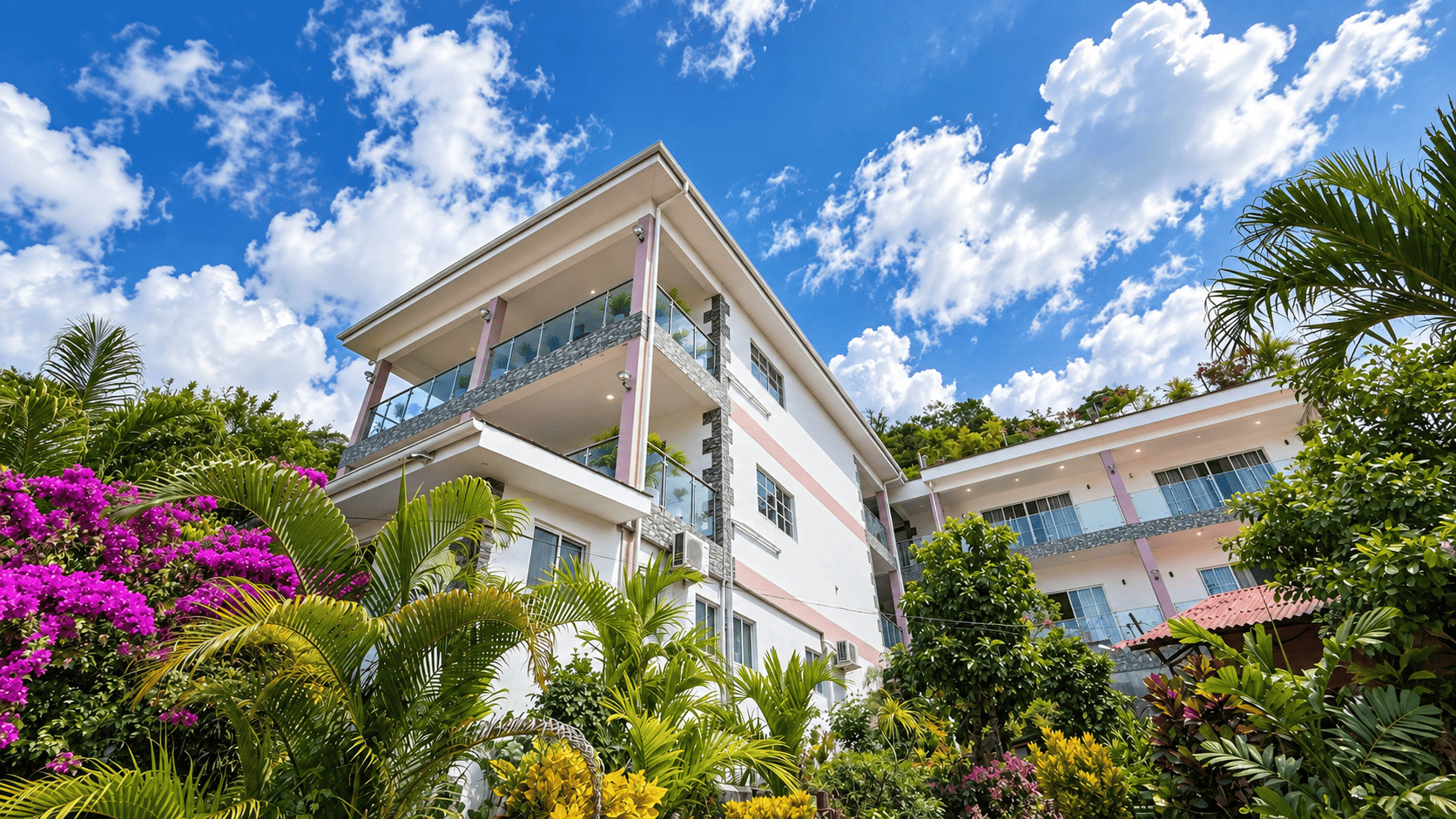 White Creole Cottage Apartment building framed by bougainvillea under a blue sky