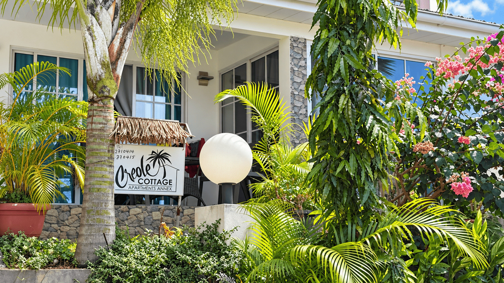 Garden at Creole Cottage Apartment with bougainvillea and the property sign