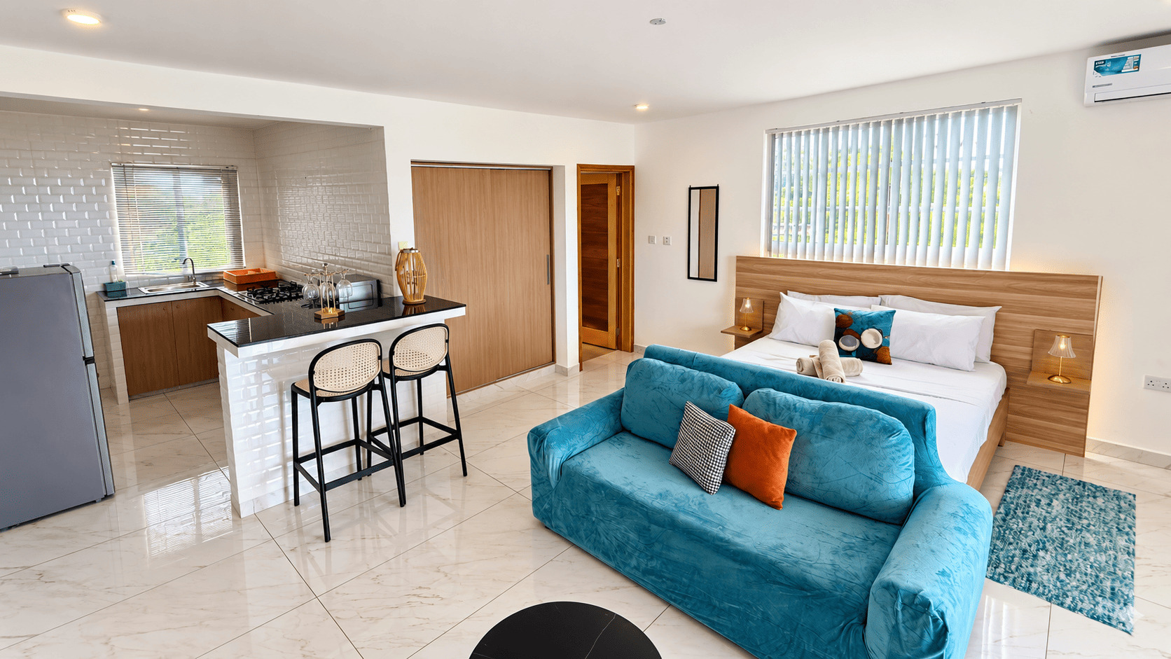 Living area of a Creole Cottage apartment with a teal sofa and open kitchen
